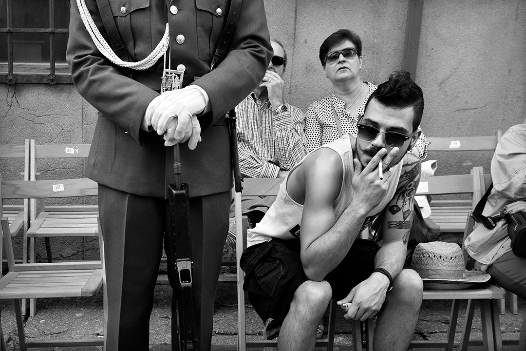A young man covering his face beside a uniformed person.